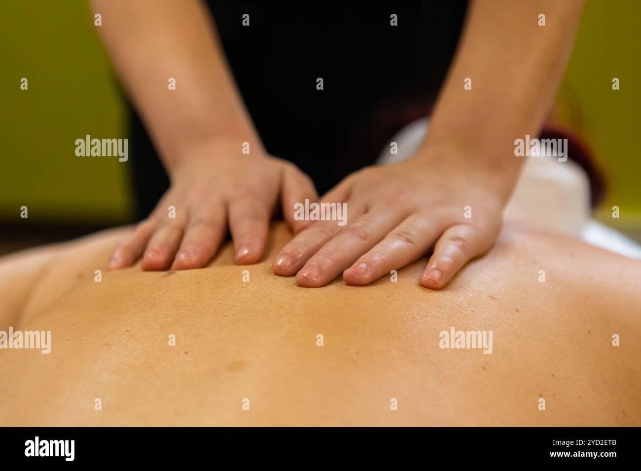 Una vista ravvicinata alle mani di un massaggiatore scorrere delicatamente le mani sopra la schiena e le spalle di una donna ha sottolineato, impastare nodi e la tensione muscolare Foto Stock