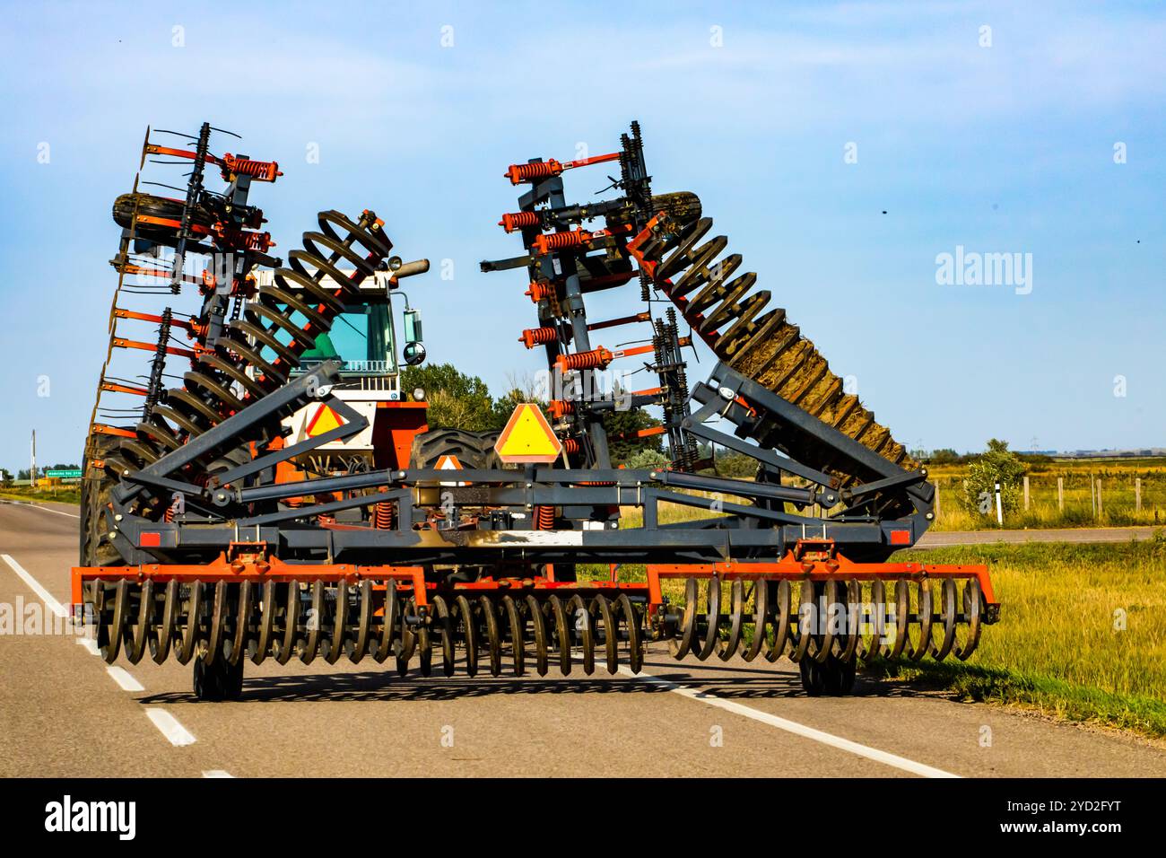 I macchinari agricoli pesanti sono attaccati alla parte posteriore di un trattore di grandi dimensioni su strada, ruotando le lame fino a raggiungere le verdure a radice e i terreni arabili dell'aratro. Con copia S Foto Stock