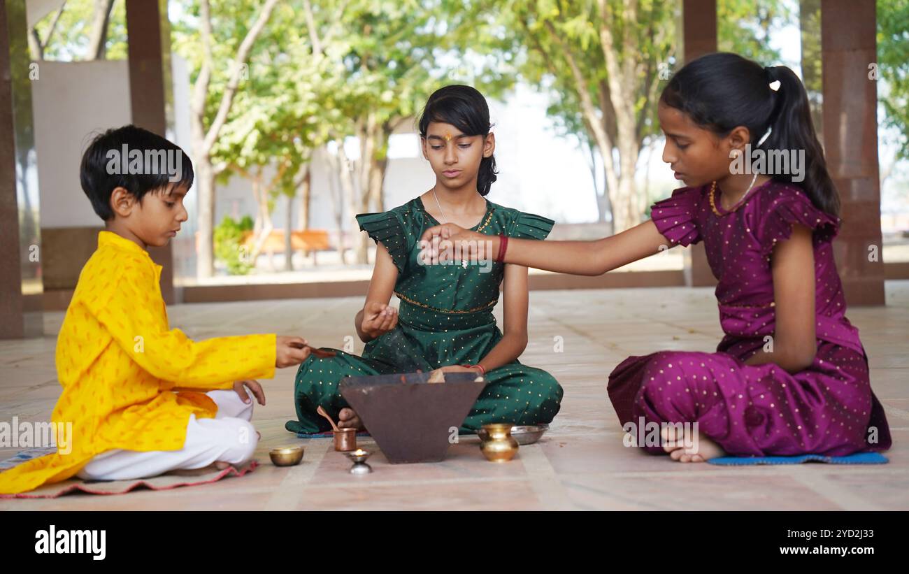 Una famiglia indiana in abbigliamento tradizionale esegue uno Yagya o un Havan, guidato da un prete, per bilanciare le energie nella loro casa. Questo pooja sacro è per armonia Foto Stock