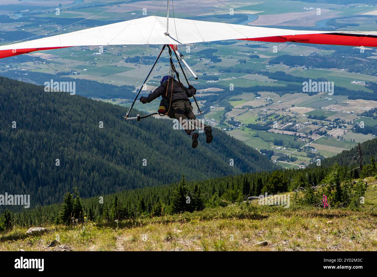 Deltaplano sulle fattorie della valle e sulle montagne Foto Stock