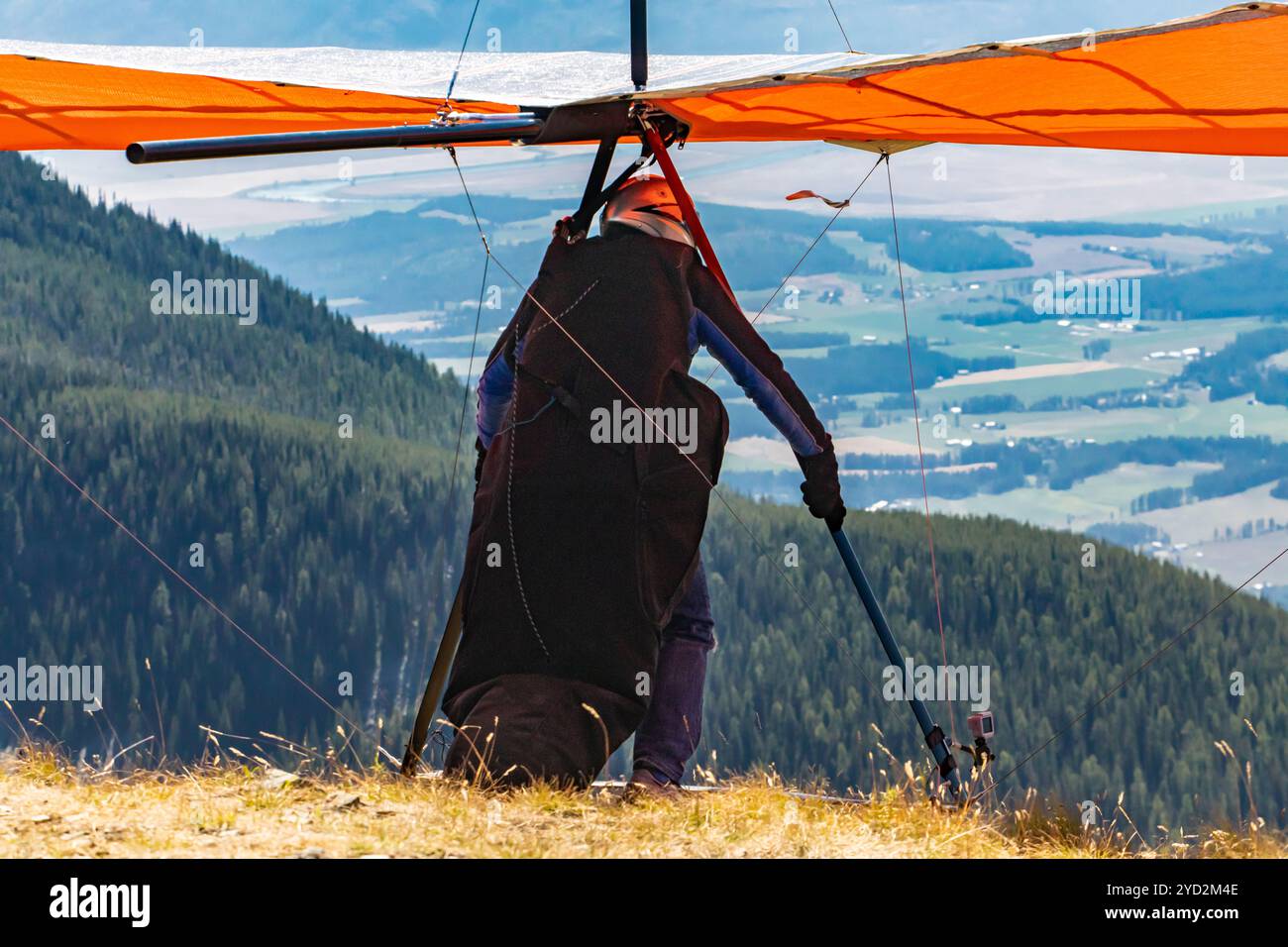 Uomo con deltaplano pronto a volare dalla cima della collina di montagna. Parapendio in cima alla collina. Un pilota di Delta Plane in procinto di avviarsi Foto Stock