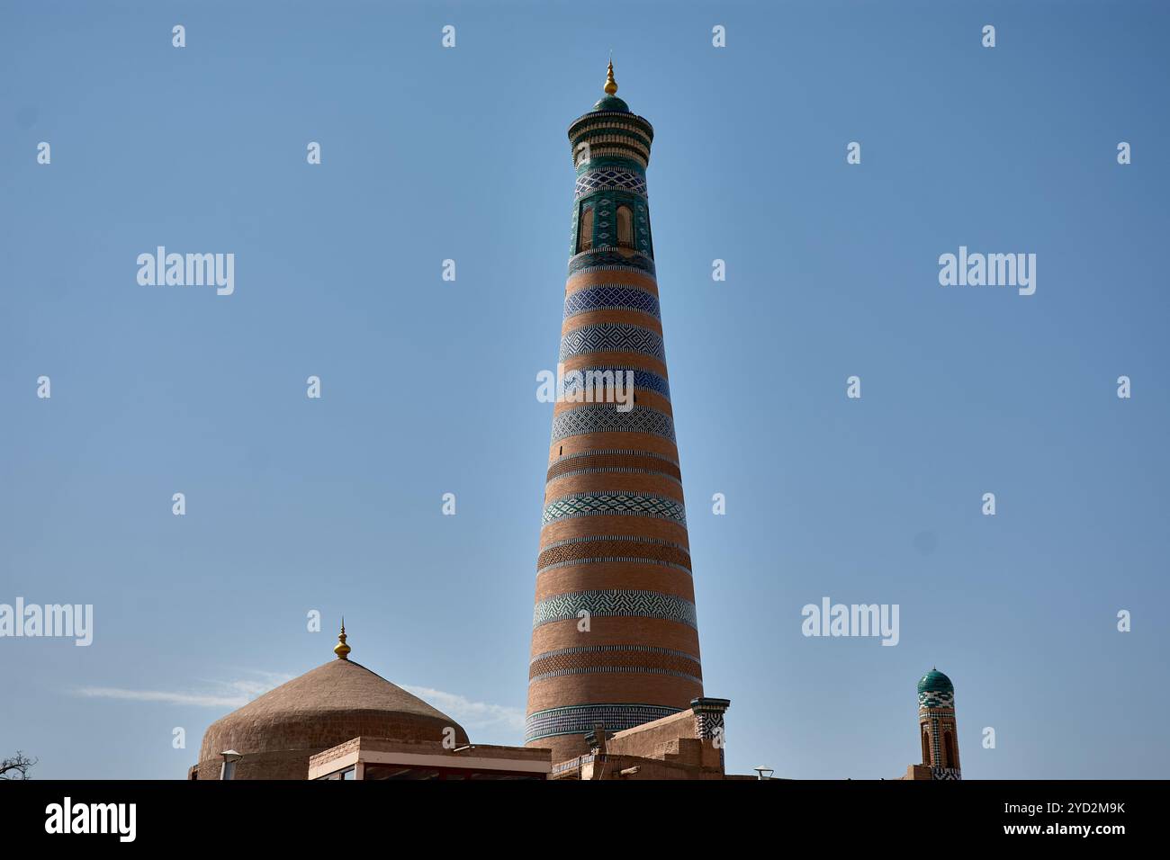 Il torreggiante minareto Islam Khoja, una struttura iconica a Khiva, Uzbekistan, conosciuta per i suoi distinti anelli con motivi blu. In piedi come il minar più alto Foto Stock