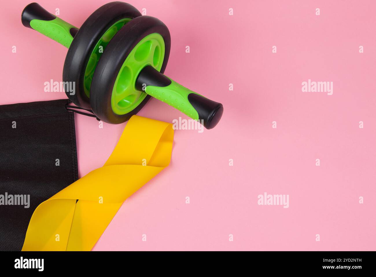 Fascia elastica gialla sportiva . Attrezzature sportive. Fascia elastica gialla su sfondo rosa. Stupido verde. Sneakers sportive. Foto Stock