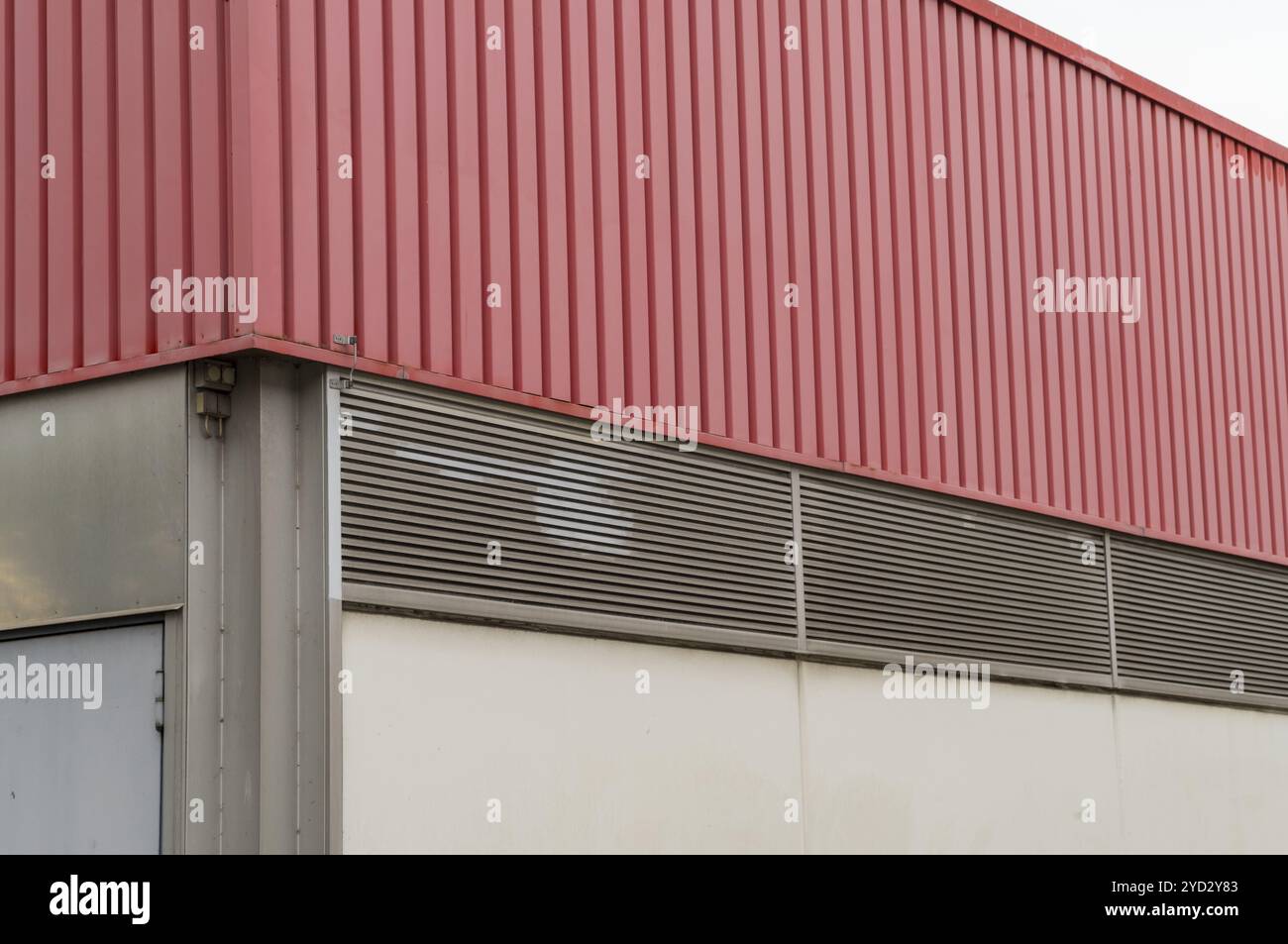 Facciata rossa dell'edificio industriale con griglia di ventilazione, che riconosce il design architettonico e la funzionalità moderni Foto Stock