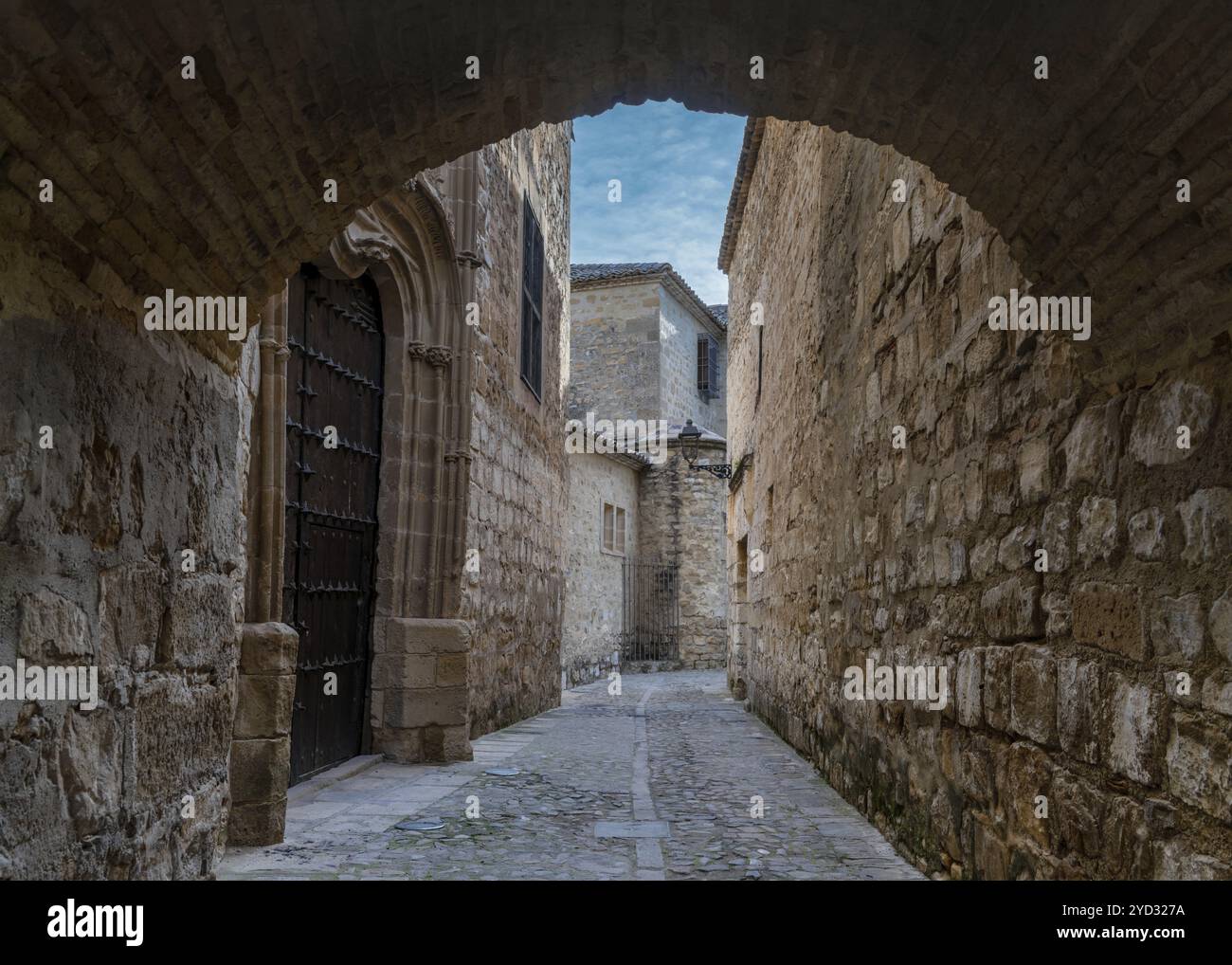 Baeza, Spagna, 5 aprile 2024: Stradina stretta e arco in pietra lungo il sentiero Paseo de las Murallas nel centro storico della città di Baeza, in Europa Foto Stock
