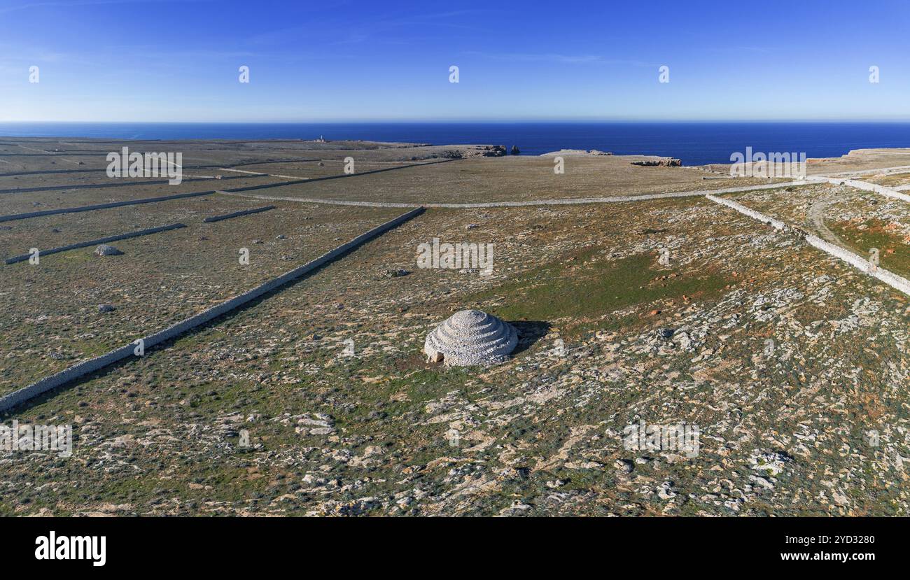 Una vista delle tipiche mura e dei campi di pietra che racchiudono le storiche case di pietra Talayot sull'isola di Minorca in Spagna Foto Stock