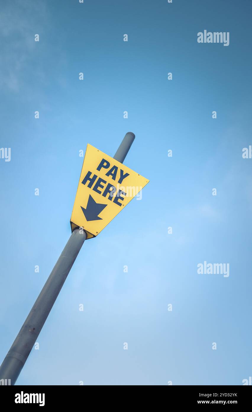 Immagine concettuale di un giallo brillante pagare qui segno contro un cielo blu con spazio di copia Foto Stock Immagine concettuale di un giallo brillante pagare qui segno contro un cielo blu con spazio di copia Foto Stock