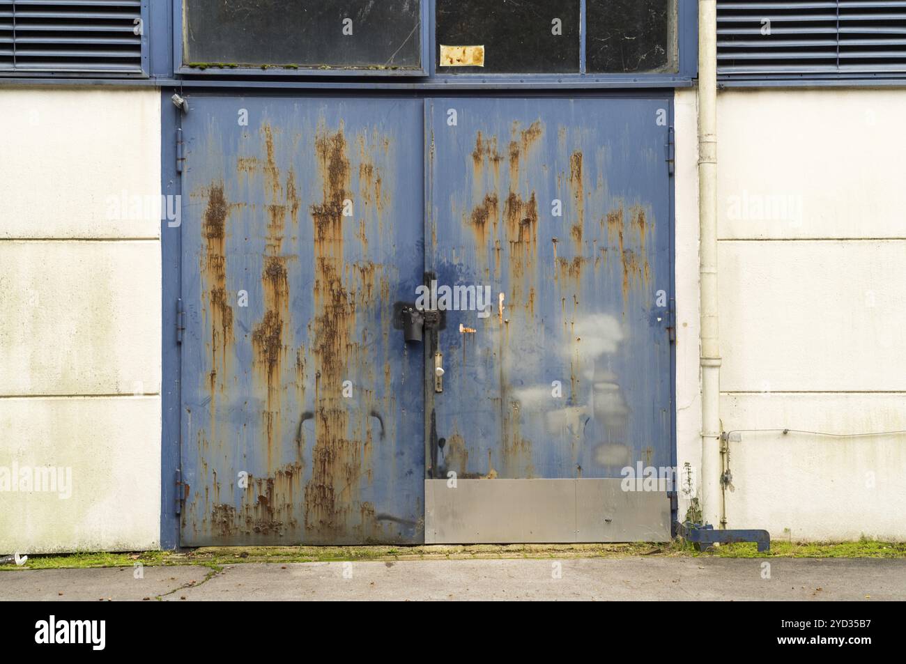 Vecchio sportello in metallo blu arrugginito con vernice e corrosione danneggiate, un quadro di decadimento e abbandono Foto Stock