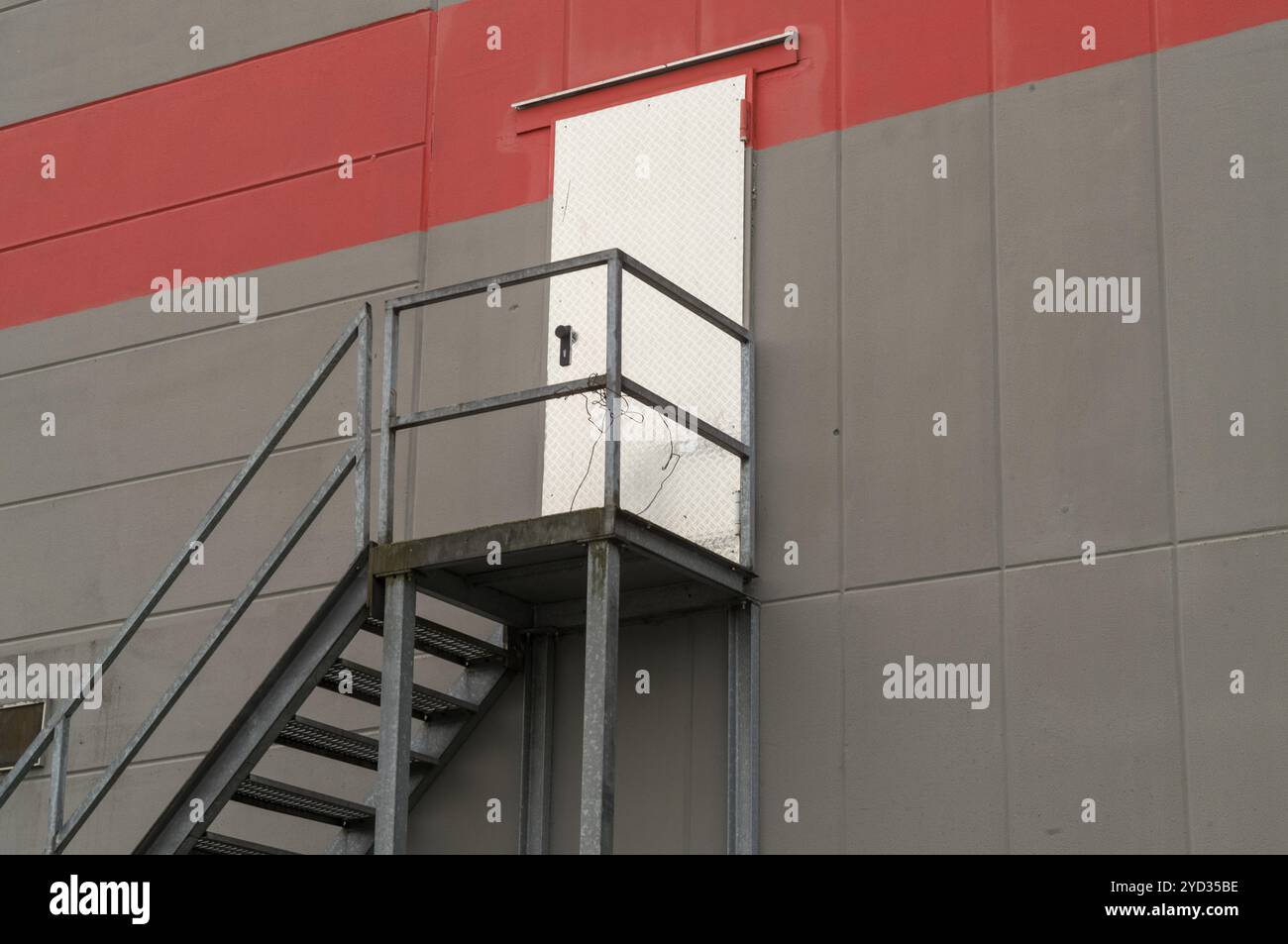 Scala metallica che conduce ad un'alta porta sul lato di un moderno edificio industriale Foto Stock