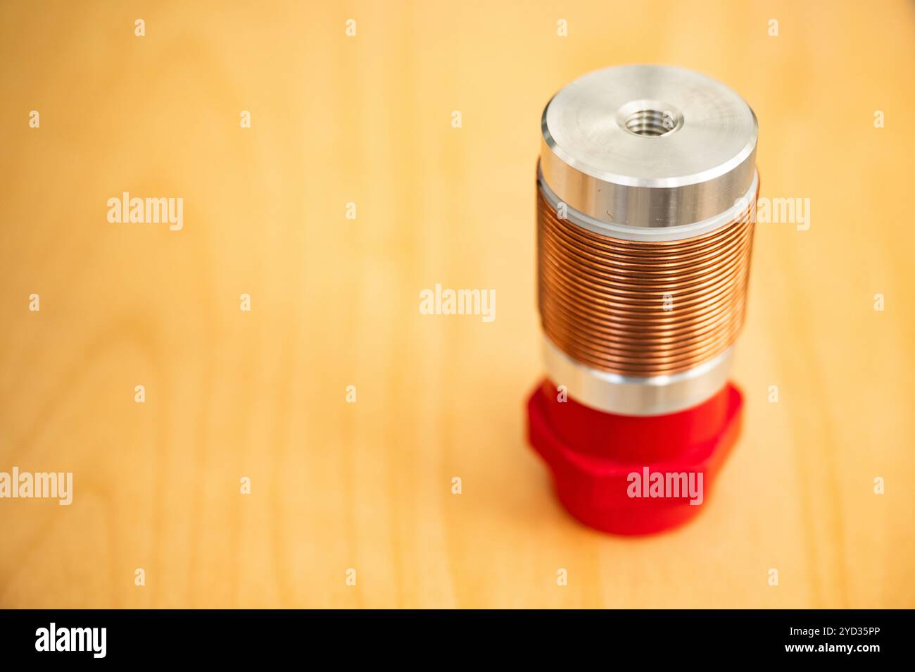 Bobina elettrotecnica in filo di rame per alta frequenza su un isolante rosso Foto Stock
