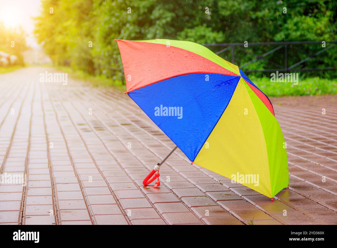 Un ombrello di colore aperto si trova sull'asfalto. Pioggia estiva. Articolo sulla scelta di un ombrello. Ombrello luminoso per bambini. . C Foto Stock