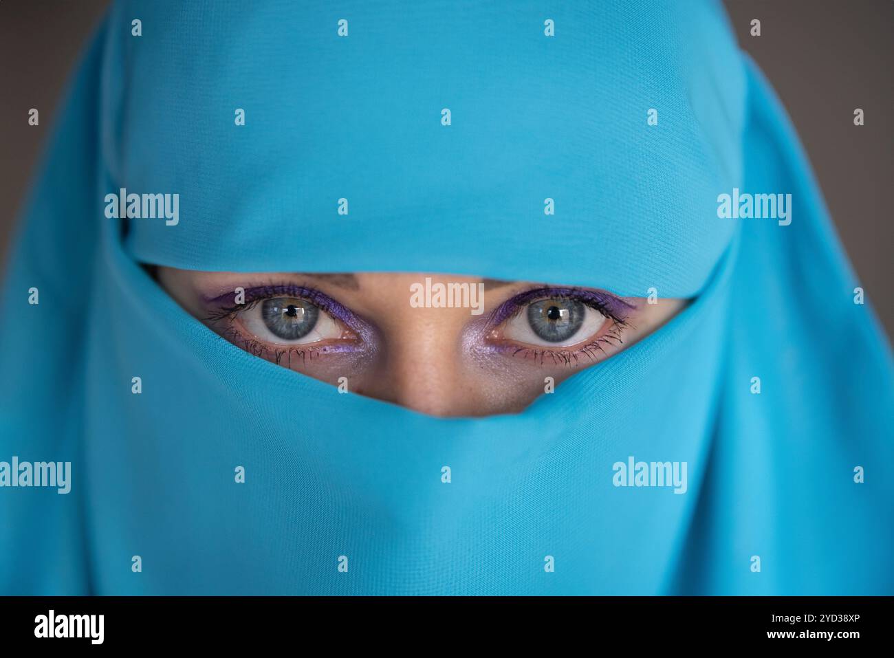 Giovane donna con gli occhi blu che indossa un tessuto turchese, che guarda la fotocamera. Foto Stock