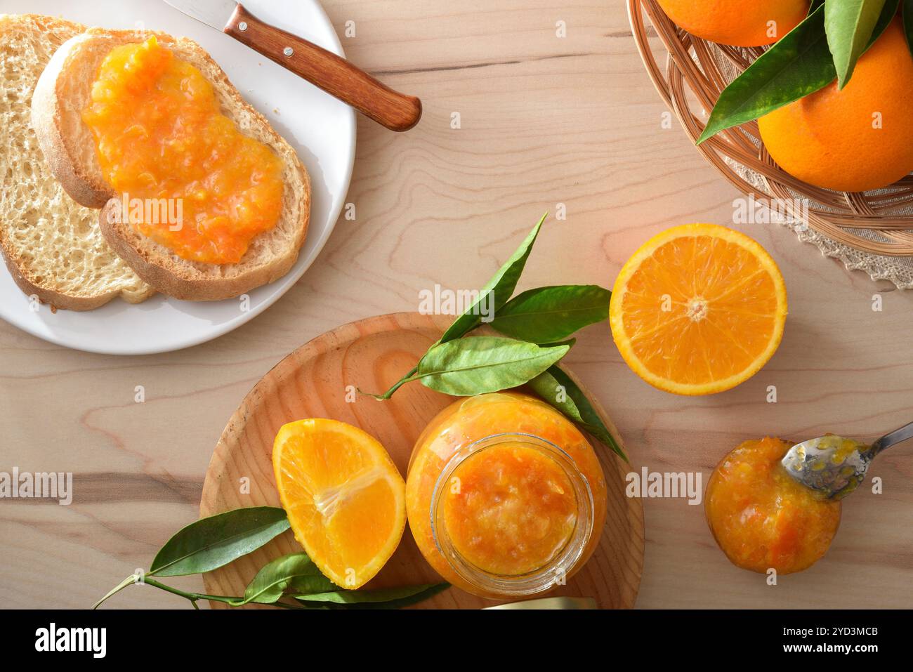 Panca da cucina con colazione preparata con marmellata d'arancia su pane tostato e vasetti e frutta in un cestino. Vista dall'alto. Foto Stock
