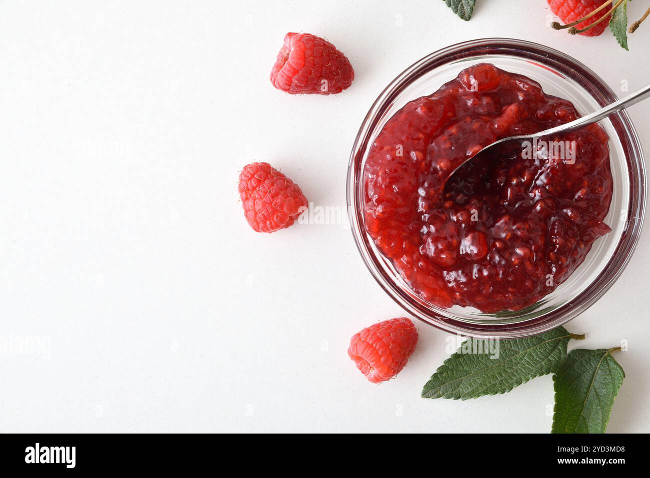 Dettaglio della ciotola di marmellata di lamponi e frutti di bosco intorno al tavolo bianco. Vista dall'alto. Foto Stock