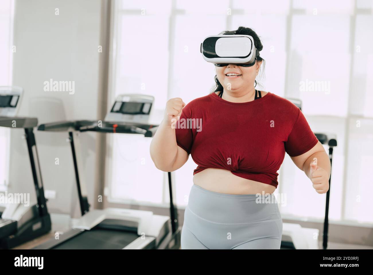 Donna che utilizza il visore VR per un'esperienza di allenamento in una palestra moderna. concetto di fitness, tecnologia e motivazione. Foto Stock