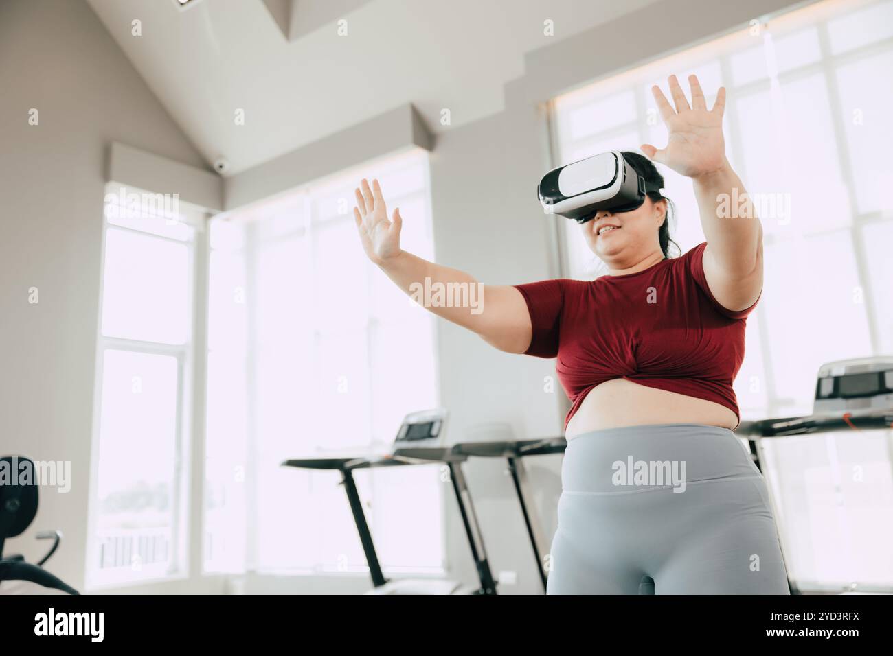 Donna che utilizza il visore VR per un'esperienza di allenamento in una palestra moderna. concetto di fitness, tecnologia e motivazione. Foto Stock