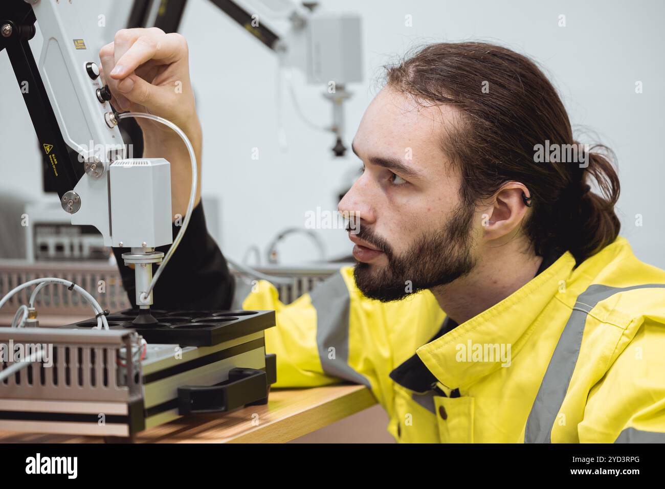 Formazione degli ingegneri maschi nel programma di robotica industriale in laboratori di ingegneria universitari apprendimento in aula braccio meccanico robot di assemblaggio. Foto Stock