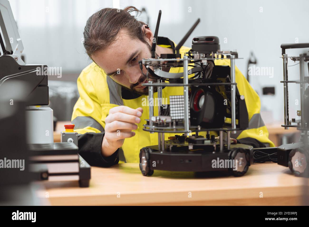 Formazione maschile degli ingegneri nel programma di robotica industriale in laboratori di ingegneria universitari apprendimento in aula assemblaggio e programmazione di robot mobili elettro Foto Stock
