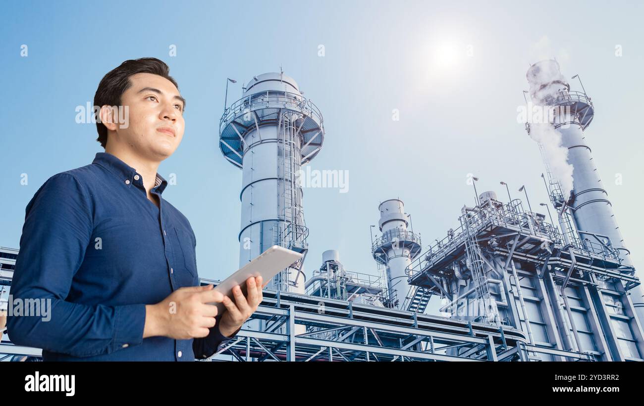 Giovane ingegnere asiatico professionista con tablet contro centrale elettrica fabbrica industriale di gas e impianto chimico di petrolio Foto Stock