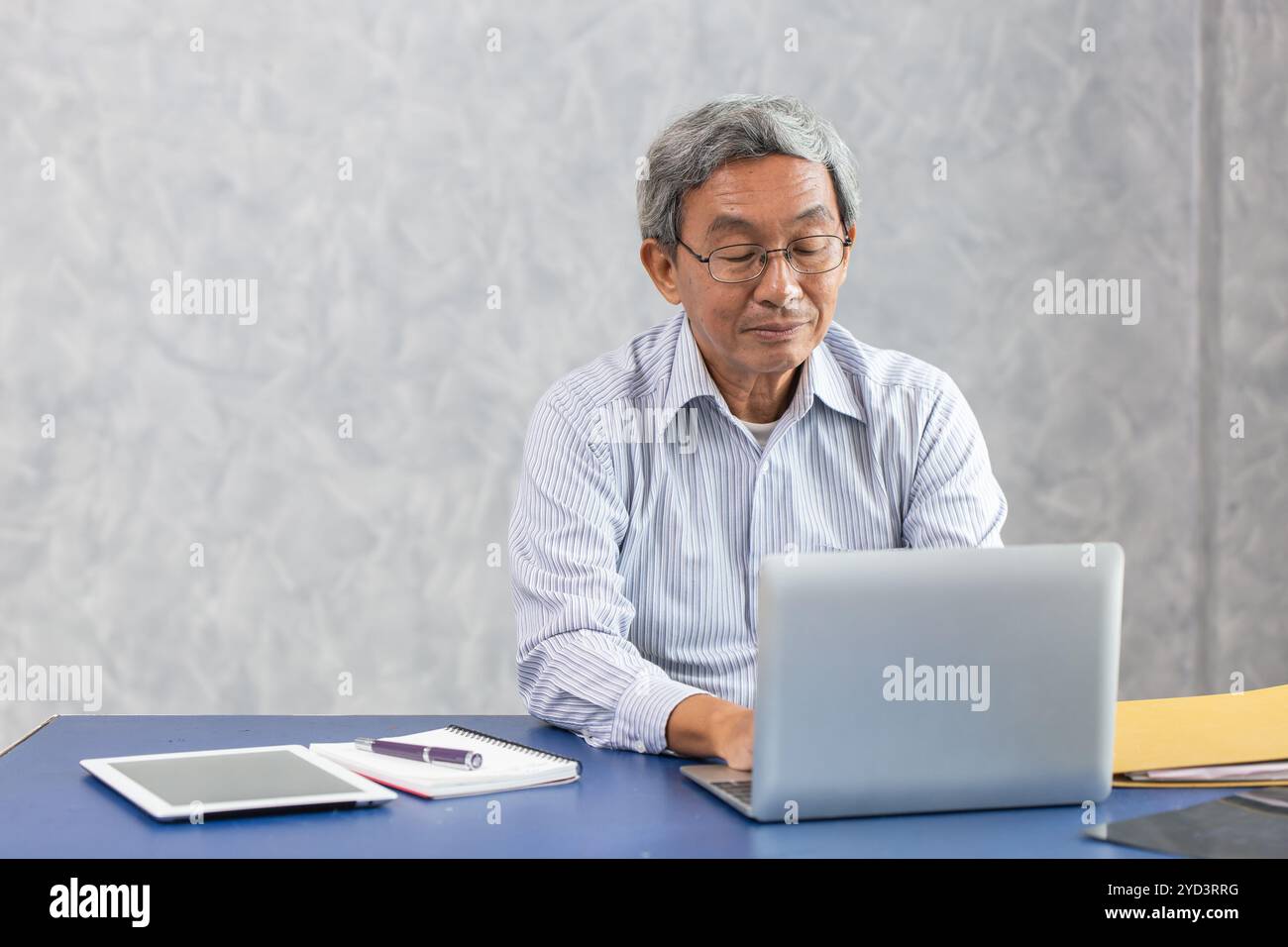 intelligente sano attivo senior asiatico affari maschio che lavora alla scrivania con computer portatile Foto Stock