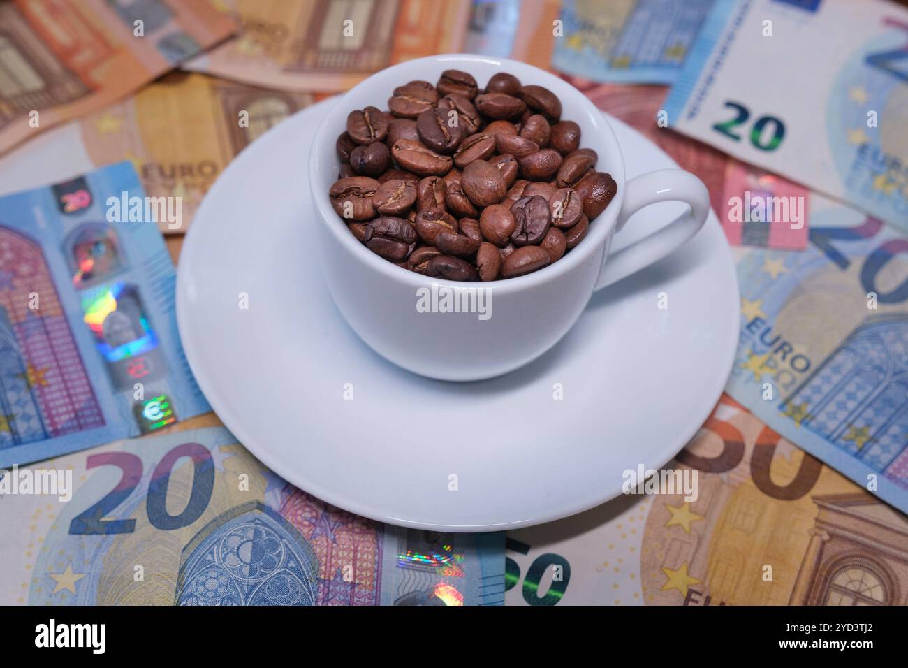 Tazza di caffè ripiena di chicchi di caffè sulle banconote in euro Foto Stock