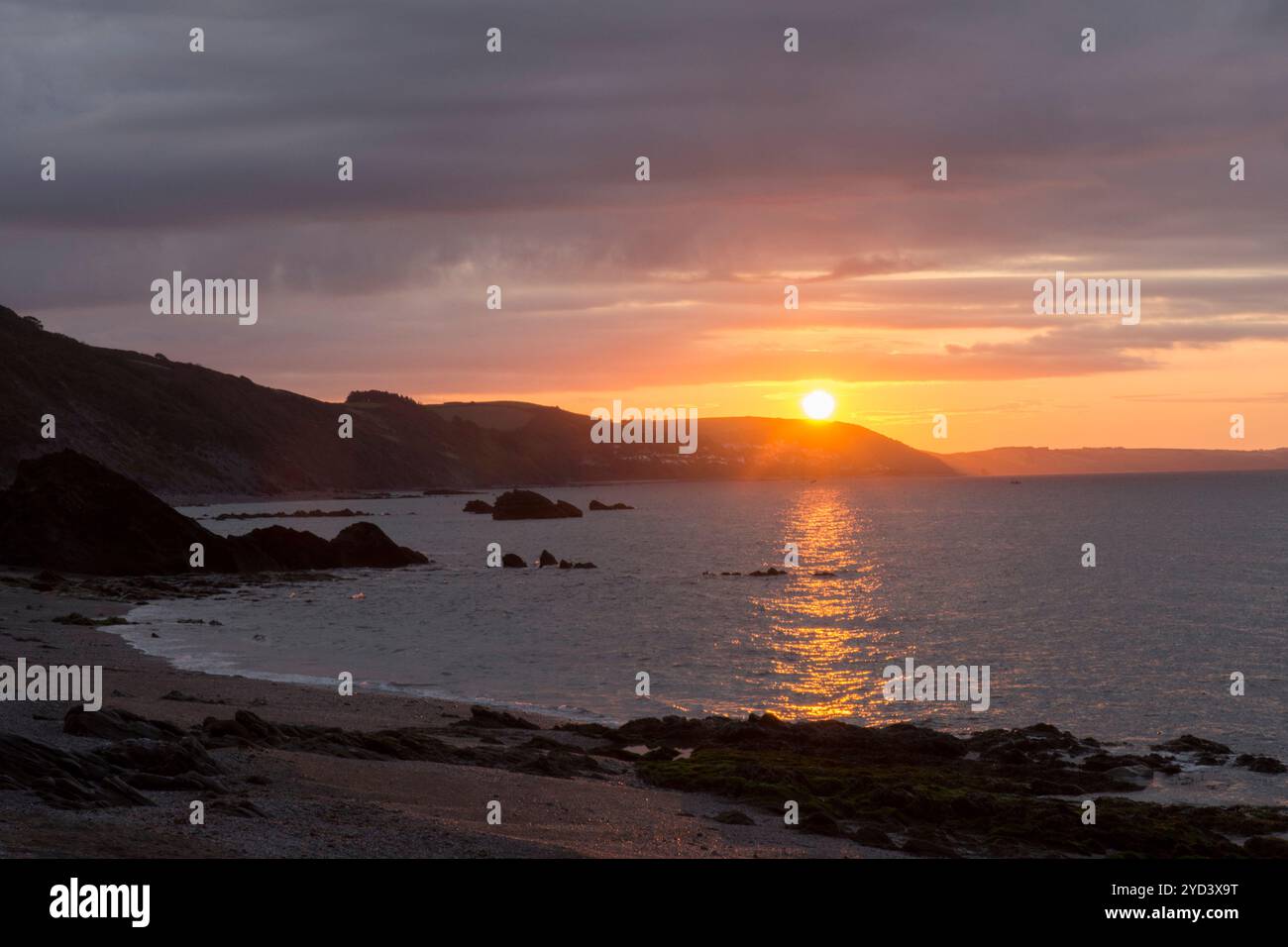 L'alba su Seaton e Downderry si riflette sul mare visto dalla spiaggia di Plaidy vicino a Looe, Cornovaglia, Regno Unito, settembre Foto Stock
