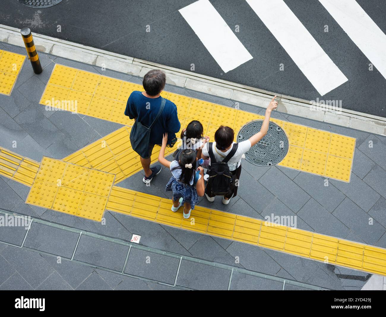 Una famiglia che aspetta di attraversare una strada a Tokyo, in Giappone. Foto Stock