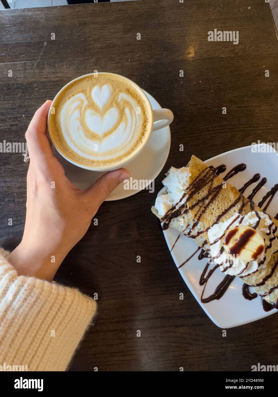 Latte con dessert crepe in un accogliente cafÃ© Foto Stock
