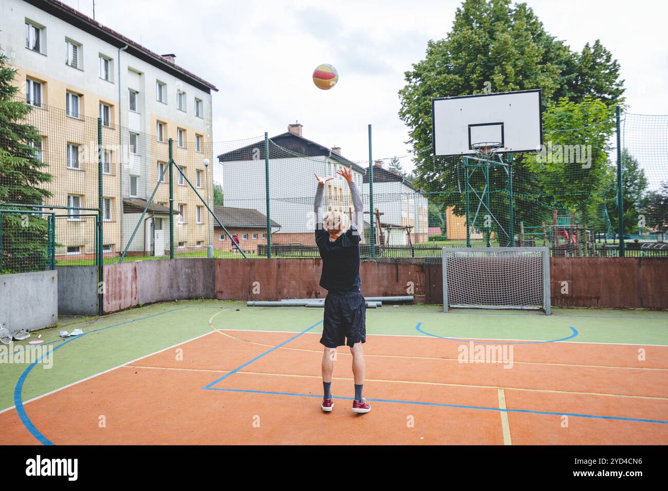 Giocatore di pallavolo che pratica l'impostazione della palla su un campo duro, concentrandosi sul controllo e la precisione durante una sessione di allenamento all'aperto. Una m calma e concentrata Foto Stock