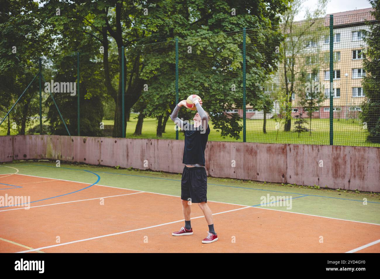 Giocatore di pallavolo che pratica l'impostazione della palla su un campo duro, concentrandosi sul controllo e la precisione durante una sessione di allenamento all'aperto. Una m calma e concentrata Foto Stock