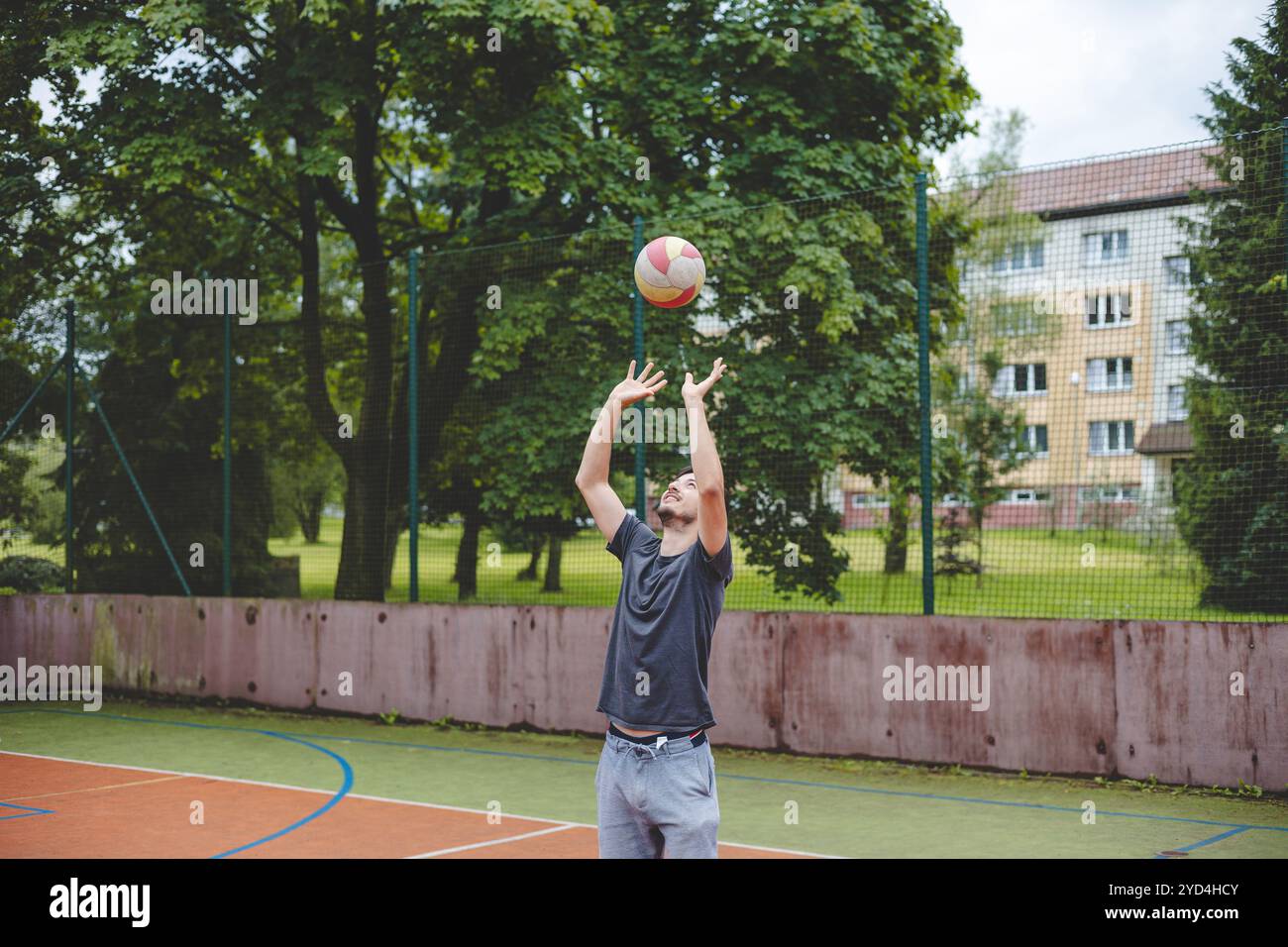 Giocatore di pallavolo che pratica l'impostazione della palla su un campo duro, concentrandosi sul controllo e la precisione durante una sessione di allenamento all'aperto. Una m calma e concentrata Foto Stock
