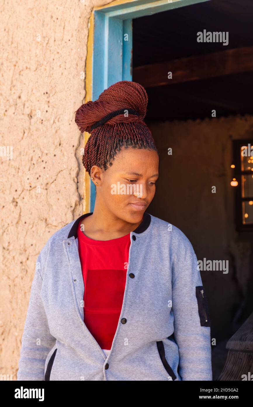 Donna africana del villaggio in piedi di fronte alla sua casa di fango Foto Stock