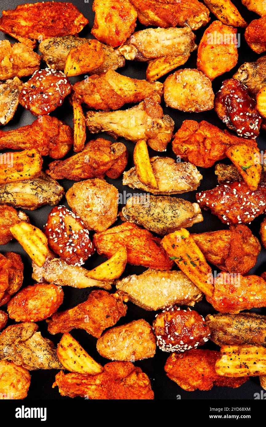 Ali di pollo croccanti fritte con diversi gusti e salse su fondo nero Foto Stock