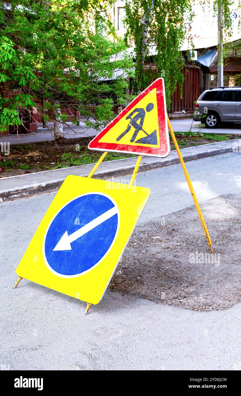Lavori stradali e segnaletica di deviazione sulla strada della città nelle giornate di sole. Cartello Road Works in città Foto Stock