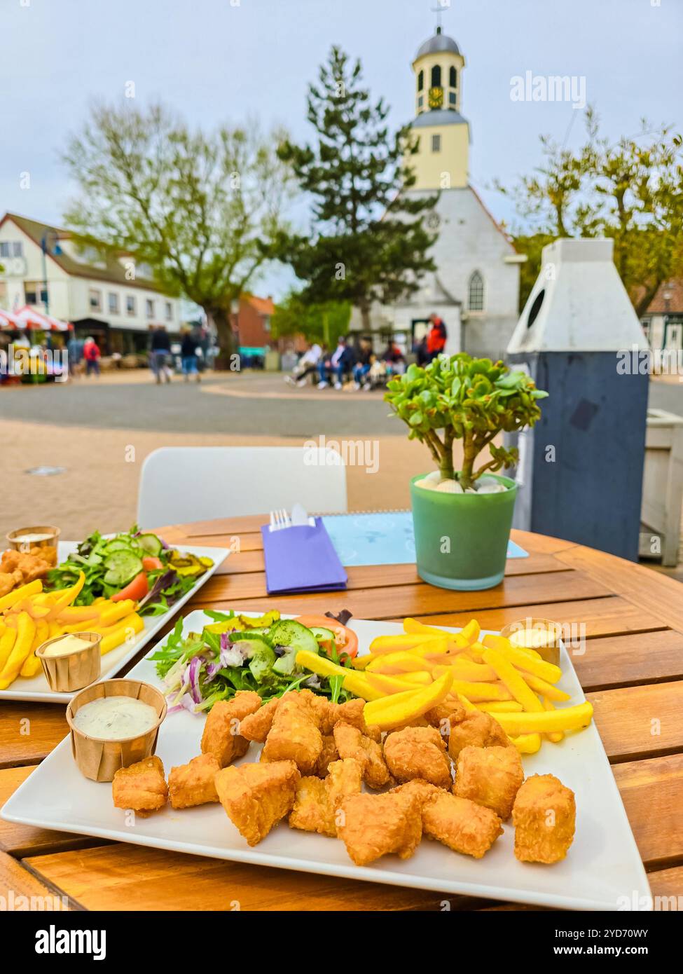 Due piatti croccanti di fish and chips, sapientemente presentati su un rustico tavolo di legno a Texel, Paesi Bassi Foto Stock