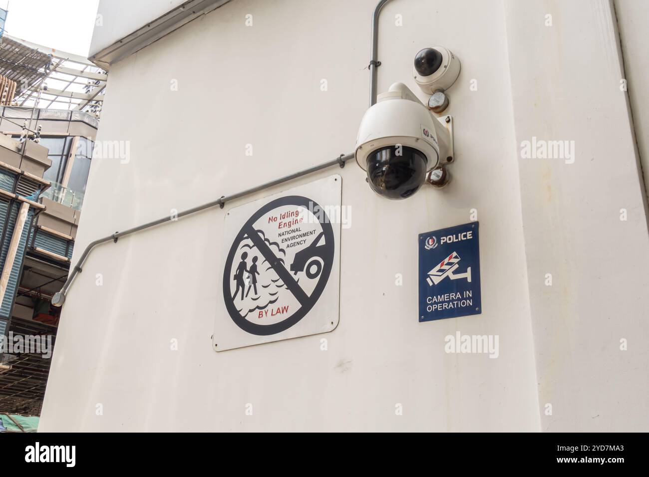 Dash camera, telecamera di sicurezza sul muro dell'edificio, quartiere finanziario di Singapore. Poster "motore al minimo non funzionante" che proibisce, Agenzia nazionale per l'ambiente Foto Stock