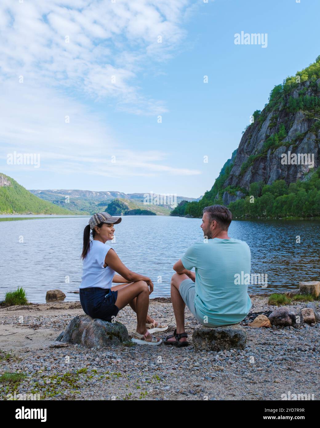 Due persone trascorrono un pomeriggio tranquillo seduto in un tranquillo lago in Norvegia. Lo splendido paesaggio delle montagne e il verde Foto Stock