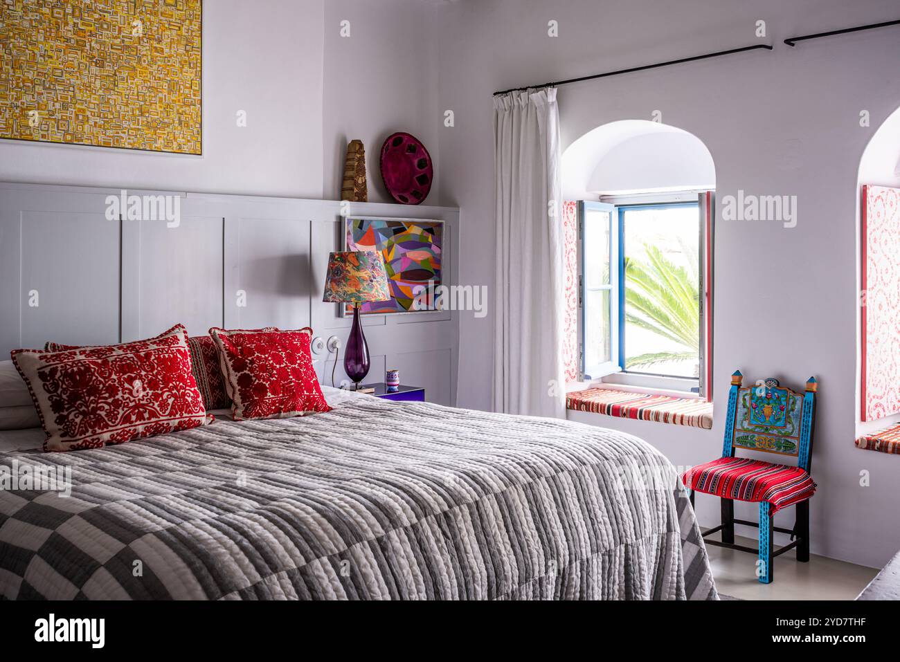 Cuscini rossi ricamati e finestre ad arco nella camera da letto di una dimora storica sull'isola di Tinos in Grecia Foto Stock