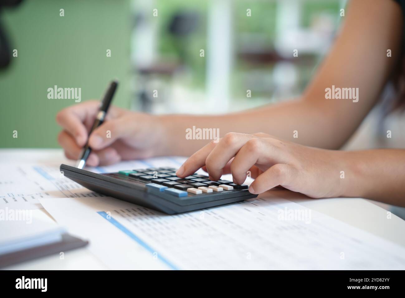 Imprenditrice contabile che analizza i grafici di investimento fattura e preme i pulsanti di calcolo sui documenti. Contabilità Foto Stock