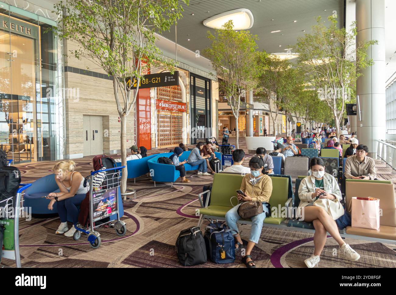 Passeggeri in una zona d'attesa di fronte ai cancelli d'imbarco, Terminal 4 dell'Aeroporto Changi di Singapore Foto Stock