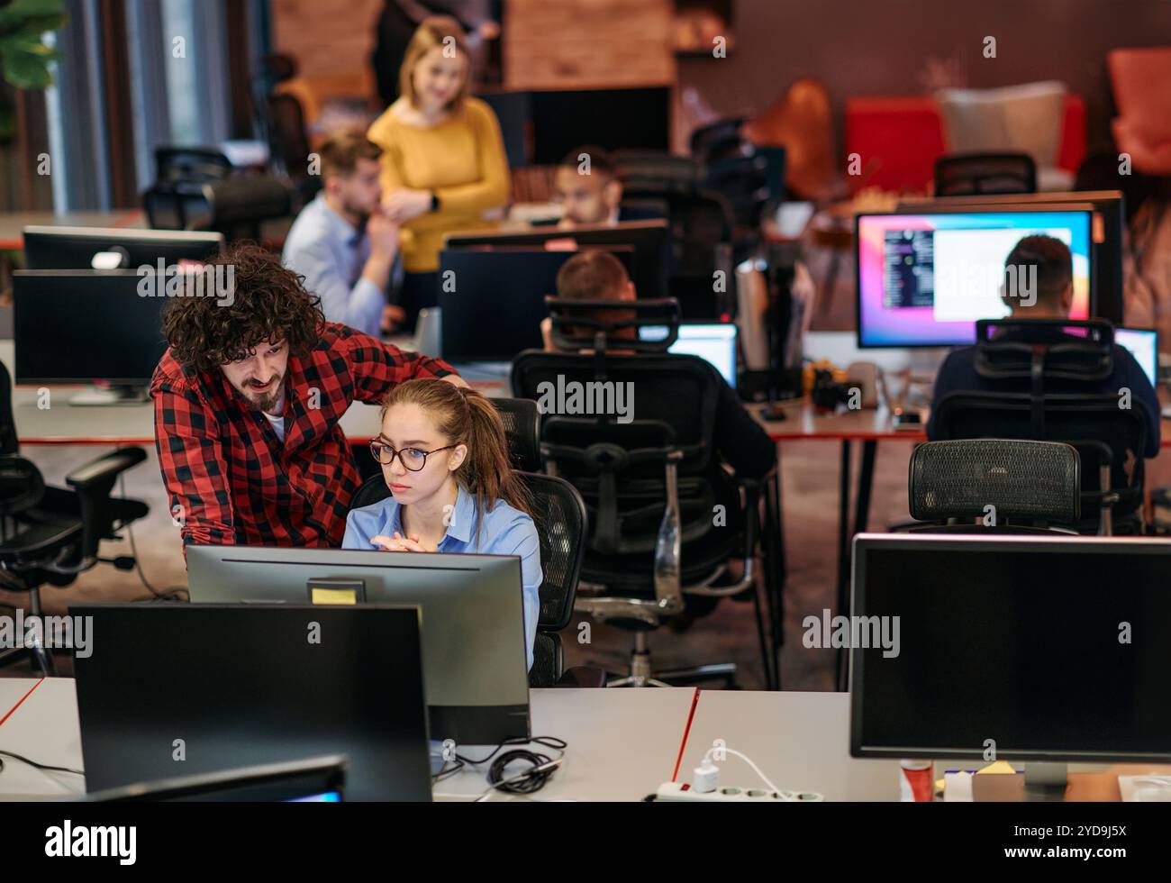 Colleghi d'affari, un uomo e una donna, si impegnano a discutere di strategie aziendali osservando attentamente un monitor di un computer, Foto Stock