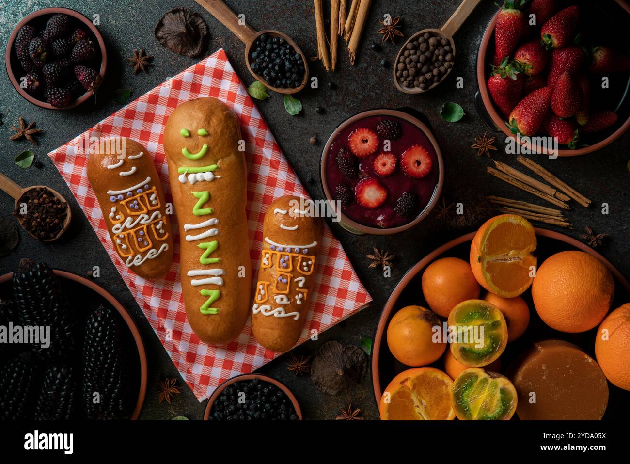 Vista dall'alto di Guaguas de pan con tazze di colada morada, cibo tradizionale ecuadoriano per il giorno dei morti, circondato dagli ingredienti per cucinare Foto Stock