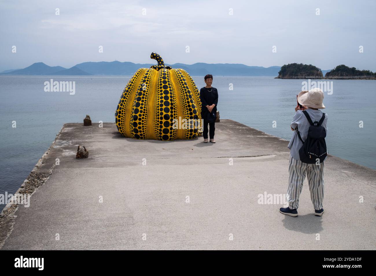 Turisti che scattano fotografie della scultura della zucca Yayoi Kusamas sull'isola di Naoshima in Giappone Foto Stock