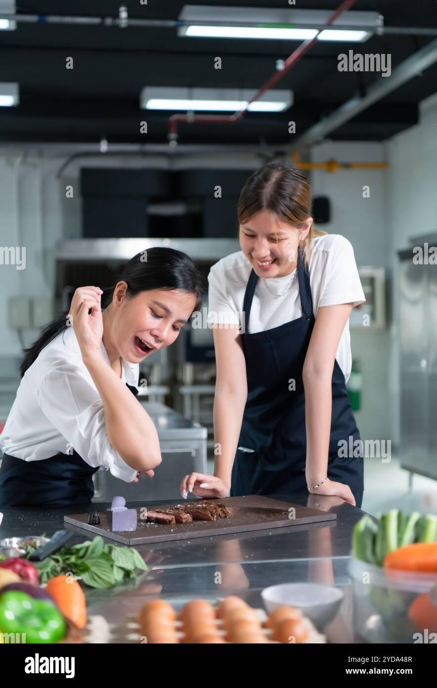 Gli studenti che cucinano apprendisti dopo che la bistecca è terminata, provano a spolverare il sale di famosi chef spolverando sopra il sale Foto Stock