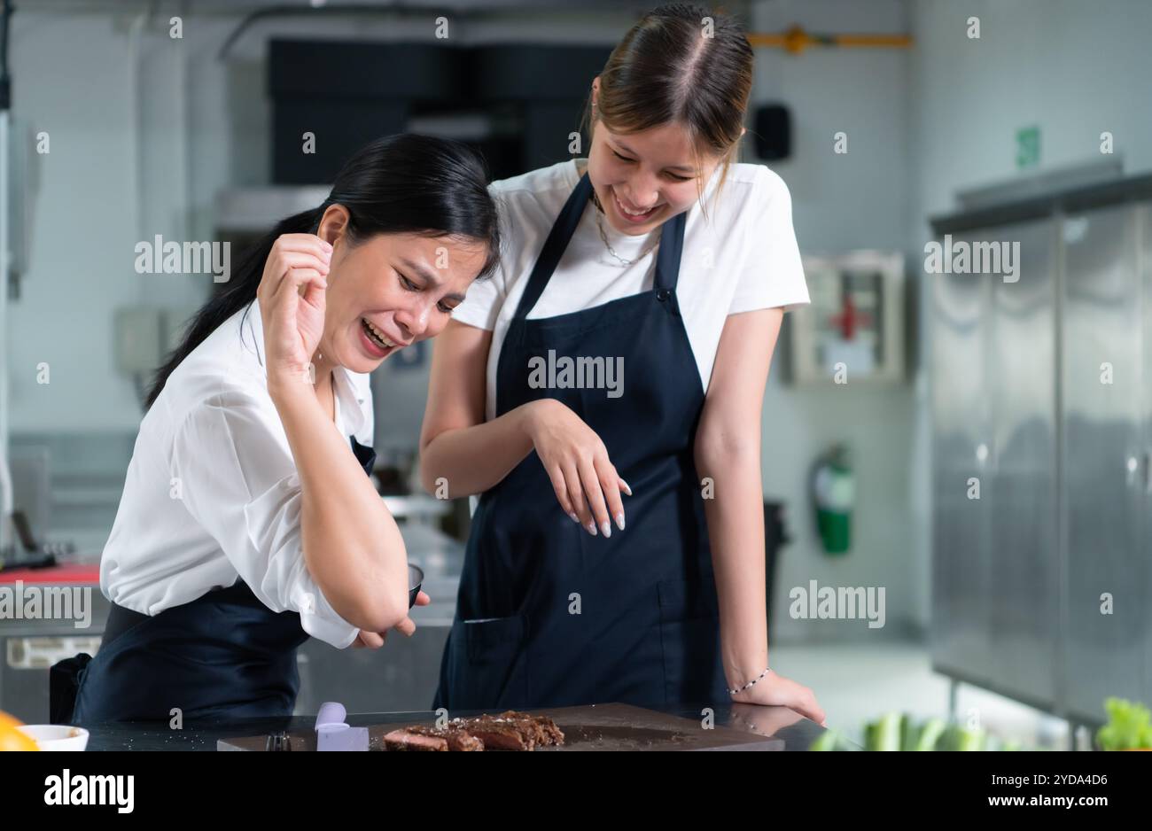 Gli studenti che cucinano apprendisti dopo che la bistecca è terminata, provano a spolverare il sale di famosi chef spolverando sopra il sale Foto Stock