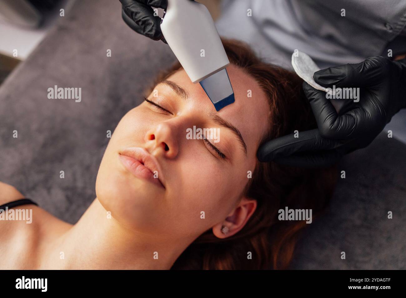 Il maestro di bellezza effettua il peeling facciale a ultrasuoni per il suo cliente. Foto Stock