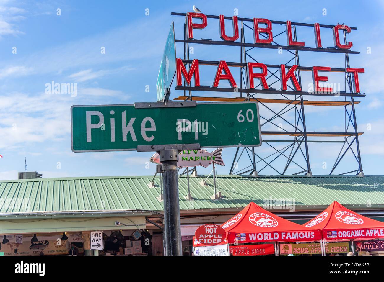 Seattle, Washington, USA - 19 settembre 2024: Cartello con il nome della strada Pike Place in verde con il cartello rosso al neon del mercato pubblico sullo sfondo di Seattle Foto Stock