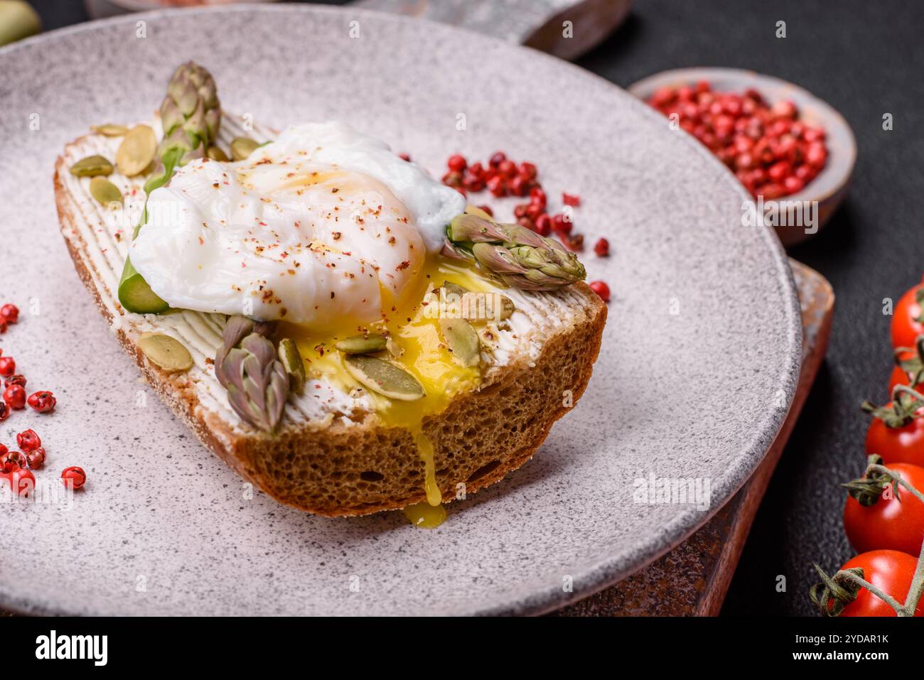 Colazione deliziosa e abbondante, con uova in camicia su pane tostato con formaggio spalmabile e asparagi Foto Stock