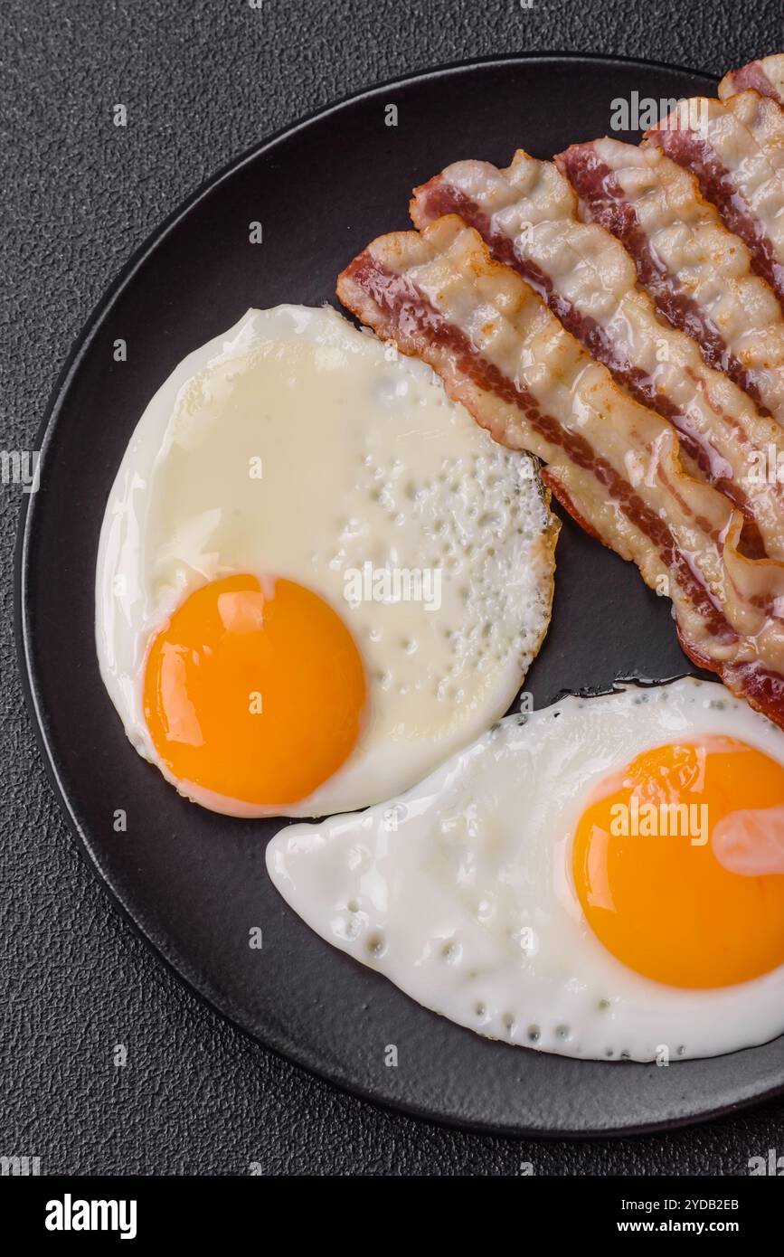 Colazione all'inglese con uova fritte, pancetta, fagioli, pomodori, spezie ed erbe aromatiche Foto Stock