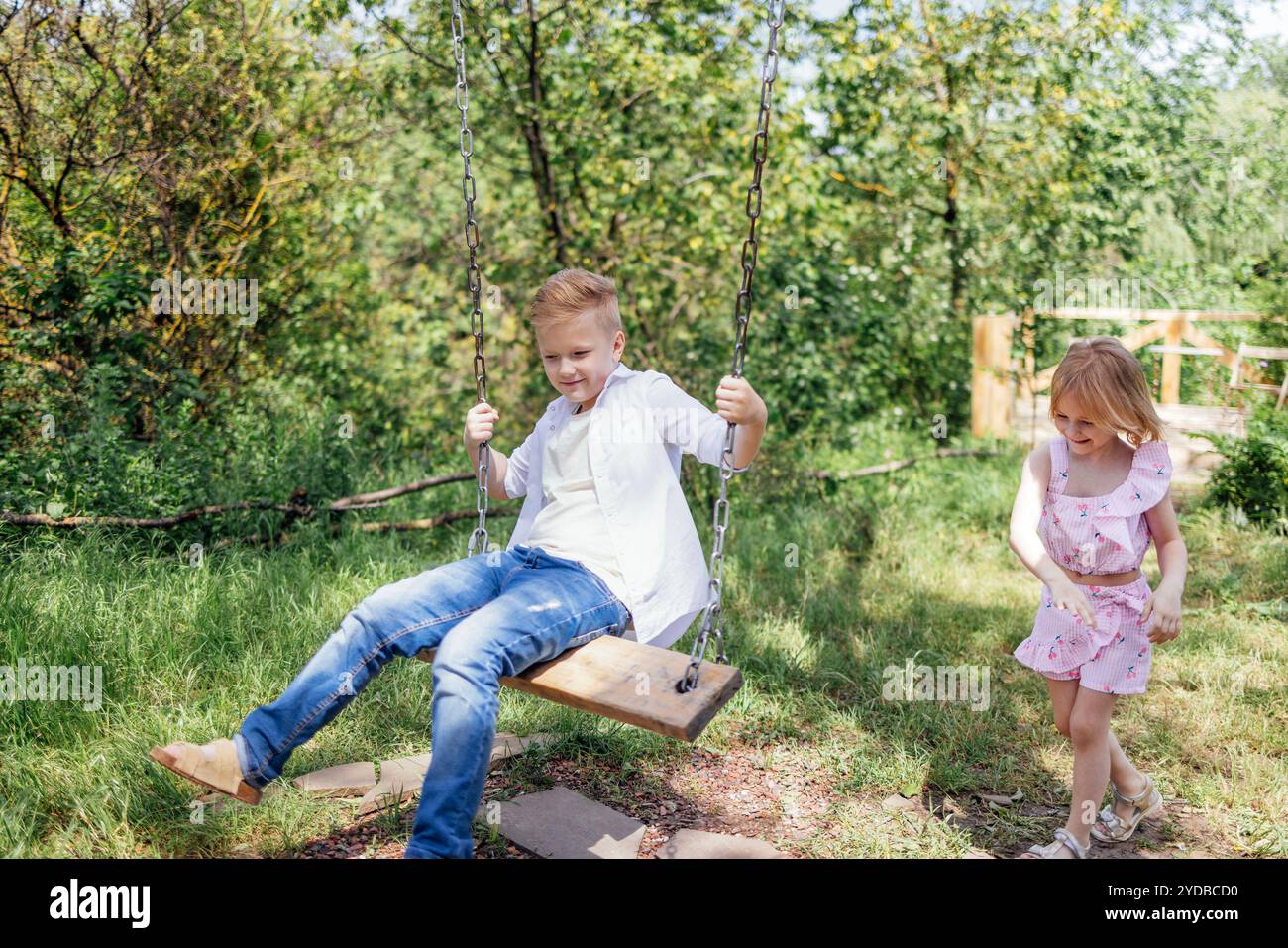 La bella bambina d'estate sta facendo oscillare suo fratello. Foto Stock